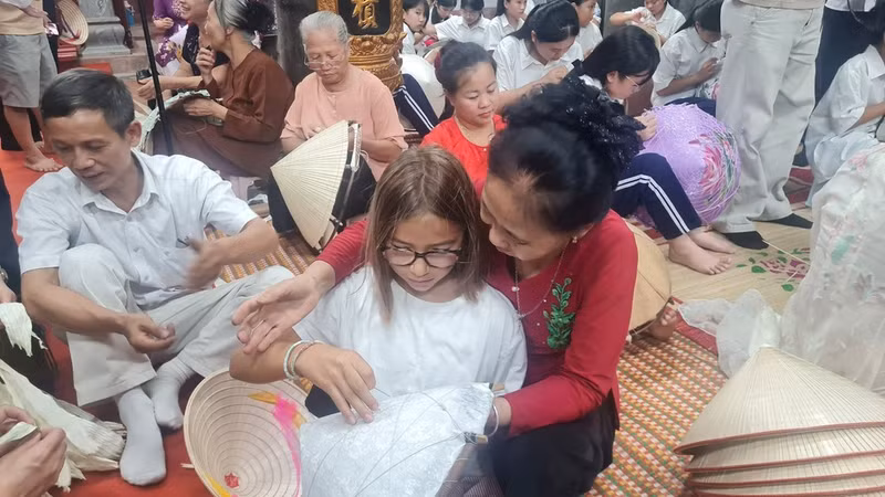 Dans la cour de la maison communale du village de Chuong, les gestes des artisans sont observés par les jeunes participants.