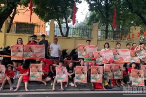 Les citoyens brandissent le supplément du journal Nhân Dân illustré par une photo de l’oncle Hô accueillant le cortège militaire sur la rue Cua Bac.