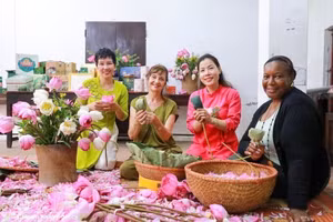 Des visiteurs découvrent l'art de parfumer le thé au lotus de Quảng An. Photo : VNA.
