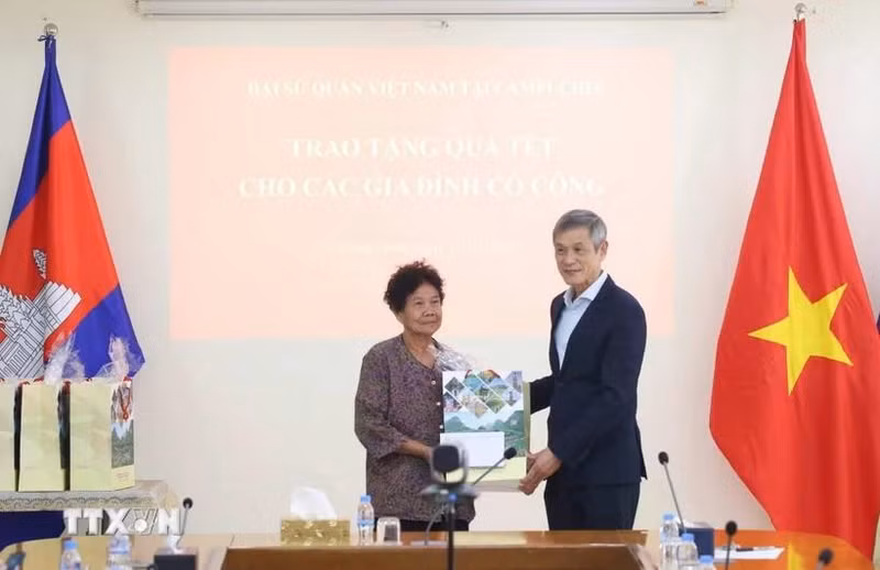 L'ambassadeur Nguyen Minh Vu remet des cadeaux du Têt à Ha Thi E, qui a contribué à la résistance contre l'armée américaine et a reçu un certificat de mérite du Premier ministre vietnamien en 2009. Photo : VNA.