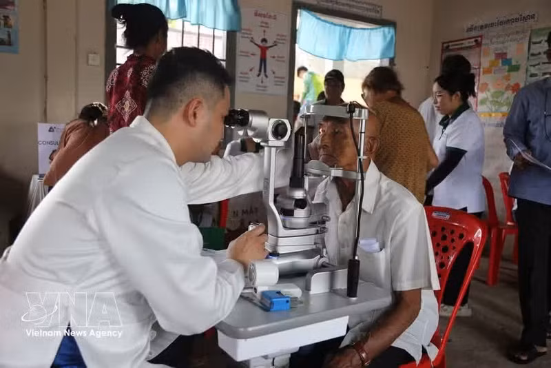 Un médecin examine le fond d’œil d’un habitant cambodgien. Photo : VNA.
