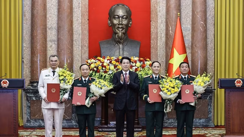 Le président Luong Cuong remet les décisions de promotion au grade de général de corps d’armée à quatre officiers supérieurs de l’Armée et de la Police populaires du Vietnam. Photo : NDEL.