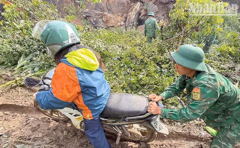 Des cadres et soldats du poste-frontière de Chieng Tuong aident les habitants à traverser une portion de route touchée par un glissement de terrain. (Photo : Quang Hung)