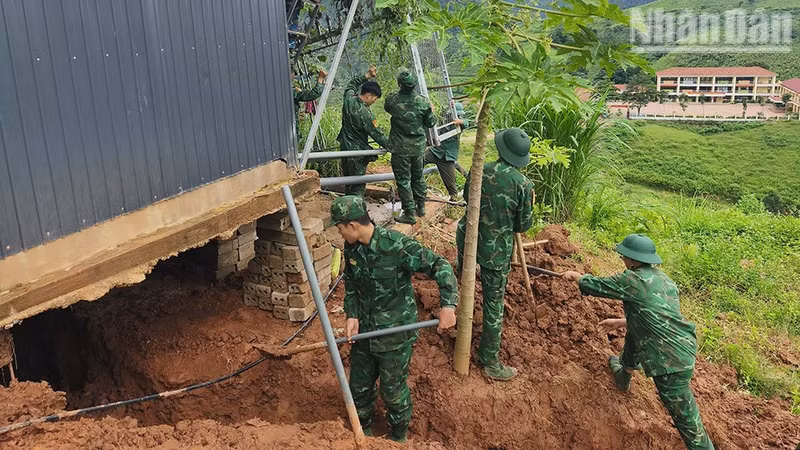 Des cadres et soldats du poste-frontière international de Long Sap aident une famille du village de Bo Sap à remédier aux conséquences d’un glissement de terrain. (Photo : Quang Hung)