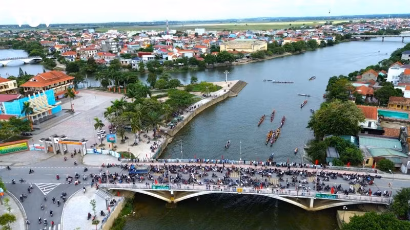 Les habitants se rassemblent sur un pont pour regarder les équipes s’entraîner à la nage et à la course de bateaux.
