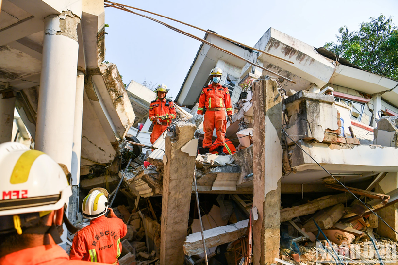 De l'autre côté du bâtiment, les secouristes de Myanmar collaborent activement avec les équipes vietnamiennes pour intensifier les recherches.