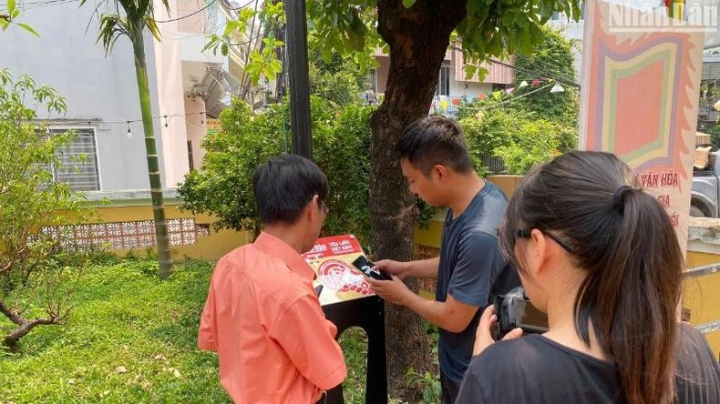 Installation d’un panneau équipé de puces NFC dans le cadre du projet « Yêu lắm Việt Nam » au site historique national de la maison communale du village de Hai Châu. Photo : NDEL.