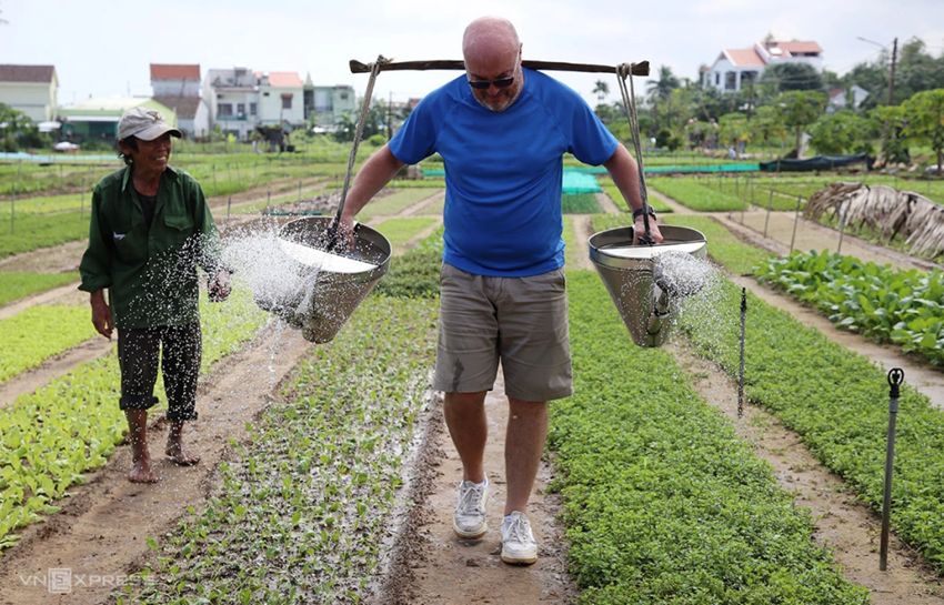 Un touriste étranger expérimente l’arrosage des légumes au village maraîcher de Tra Que. Photo : VnExpress. Un touriste étranger expérimente l’arrosage des légumes au village maraîcher de Tra Que. Photo : VnExpress.