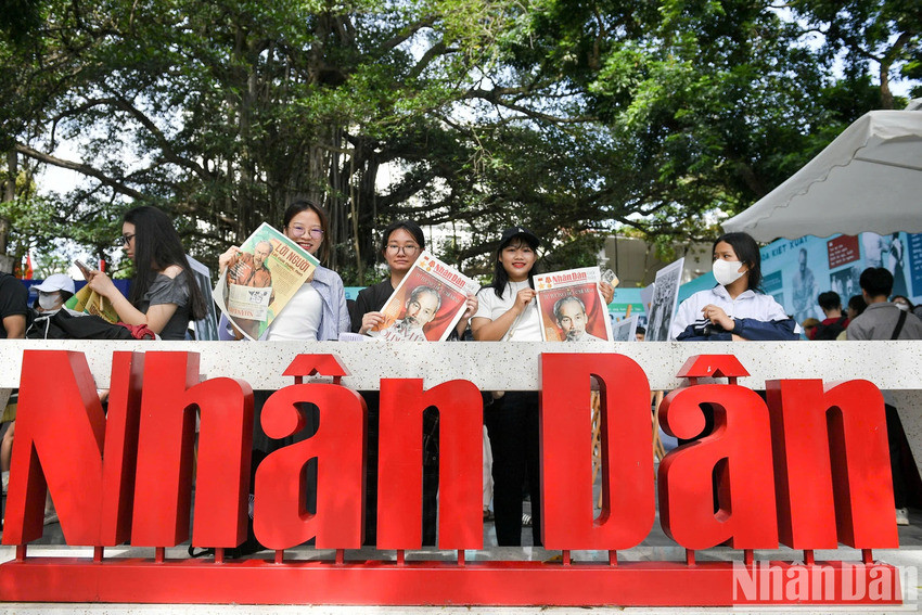 Des lecteurs rayonnants de joie après avoir reçu le supplément spécial du Journal Nhân Dân. Photo : Nhân Dân.