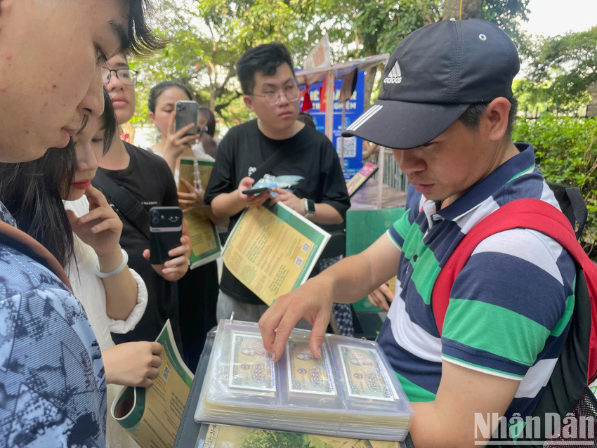 M. Vinh partage sa passion pour sa collection avec les jeunes visiteurs intéressés. Photo : Nhân Dân.