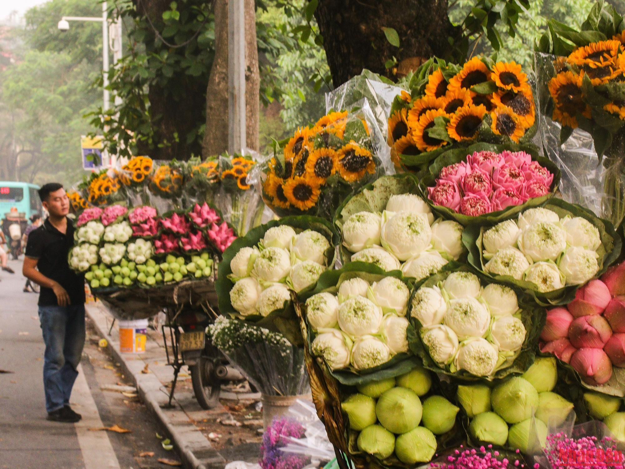 Un marchand ambulant en haut de la rue Thuy Khuê (quartier Thuy Khuê, arrondissement de Tây Hô, Hanoï) propose des fleurs d'automne typiques telles que le lotus et le tournesol…