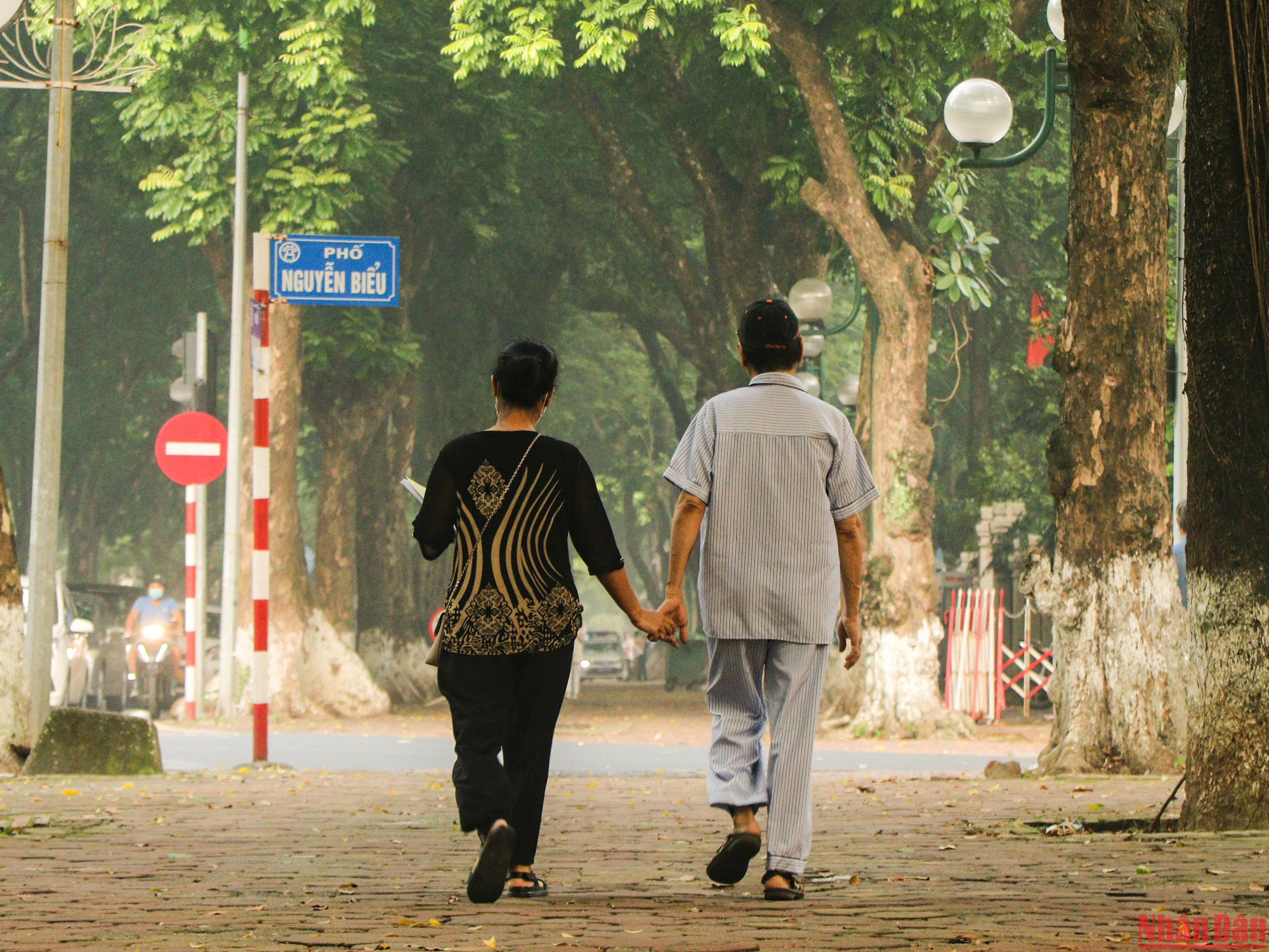 Un couple de personnes âgées, main dans la main, fait une promenade, et profite de l’arrivée de l’automne.