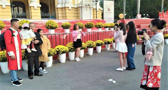 M. Thanh (du district de Gia Lam) et ses enfants prennent des photos devant l'Opéra de Hanoi pour profiter de l’atmosphère printanière. Photo : Quang Tuan/NDEL.