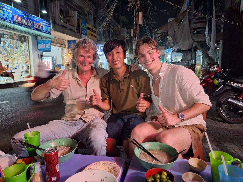 Le propriétaire d'un stand de restauration de rue à Chau Doc (au milieu) prend une photo avec le mari et le fils de Nathalie. Photo : Vnexpress.