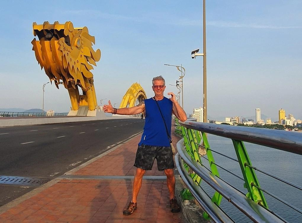 Grant Wilson pose près du pont du Dragon à Da Nang en mai 2025. Photo : Vnexpress.