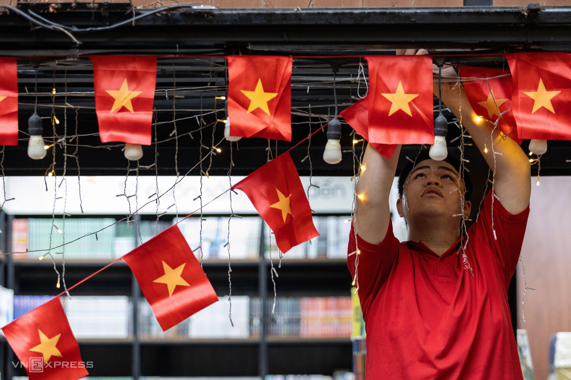 Phuong Duy, 20 ans, installe des fanions sur un stand pour enfants, rue des livres Nguyen Van Bình (1er arrondissement de Hô Chi Minh-Ville)