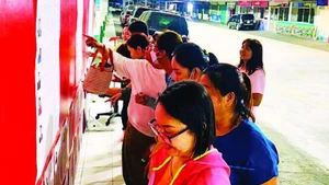 Des ouvriers de l’entreprise Pouyuen Vietnam Co., Ltd. consultent les biographies des candidats affichées dans l’enceinte de l’usine.