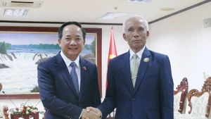 Trinh Van Quyêt (à gauche), secrétaire du Comité central du PCV et chef de sa Commission de la sensibilisation, de l’éducation et de la mobilisation des masses, et Khamphan Pheuiyavong, secrétaire du Comité central du PPRL et président de sa Commission de la propagande et de la formation, se serrent la main, à Vientiane, le 1er décembre. Photo : VNA 