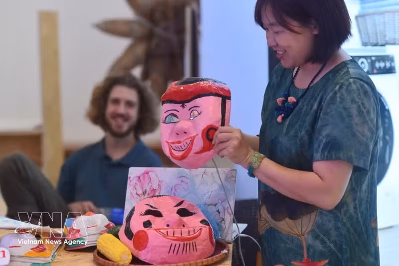 Des visiteurs étrangers sont séduits par les masques artisanaux du marché créatif «Kết duyên Sáng tạo». Photo : VNA