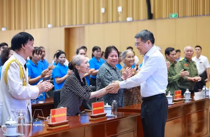 Le PM Le Minh Hung et des familles bénéficiaires de l'aide sociale. Photo: VNA