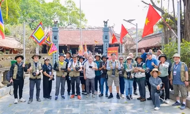 Un groupe de photographes internationaux sur le site historique de la maison communale du village de Tho Ha.