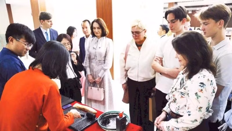 Des touristes étrangers apprécient l'expérience des tablettes de bois gravées. Photo : nhadan.vn 