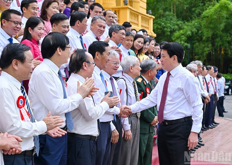 Le président Luong Cuong (à droite) serre la main des journalistes chevronnés, à Hanoi, le 20 juin. 