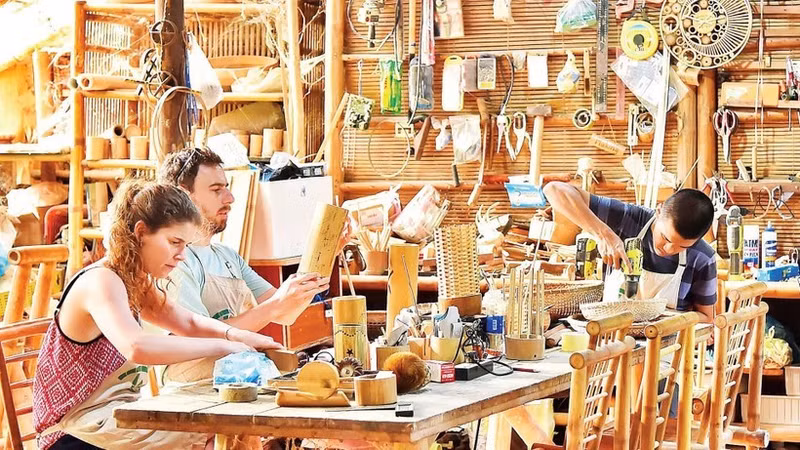 Des touristes fabriquent leurs propres souvenirs en bambou dans un atelier d'artisanat à Da Nang. Photo : nhandan.vn
