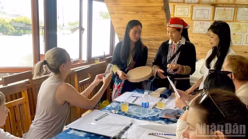Les touristes d’ecouvrent les dessins à la cire d'abeille et teinte à l'indigo au cœur du décor doré de Ta Van. Photo : NDEL.