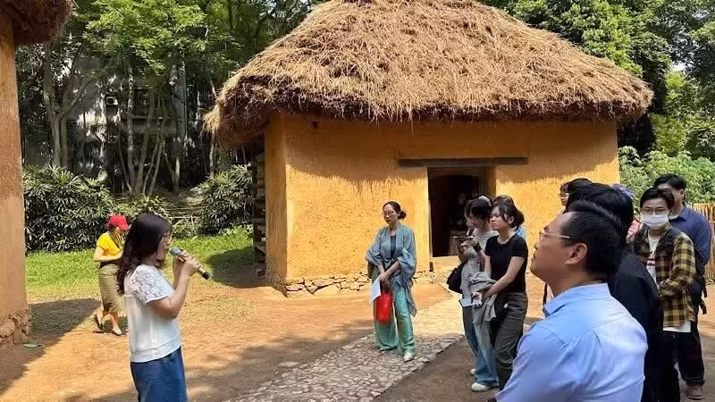 Des touristes visitent une maison de l'ethnie minoritaire Ha Nhi au Musée d'ethnologie du Vietnam. Photo : NDEL.