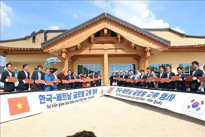 Les délégués sud-coréens et vietnamiens signent des tuiles à contruire le toit de la Maison communautaire de Bonghwa. Photo : VNA.