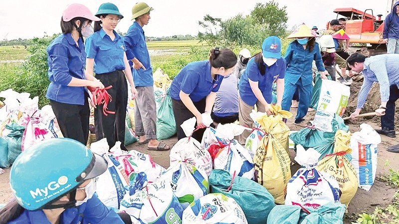 Des membres de l'Union des jeunes et des volontaires de la commune de Nam Phu, ainsi que les forces vives et la population, ont construit des sacs de sable pour empêcher l'eau du fleuve Rouge de déborder dans les villages. Photo : NDEL