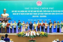 Le Premier ministre Pham Minh Chinh offre des fleurs de félicitations aux jeunes Vietnamiens exemplaires. Photo : VNA. 