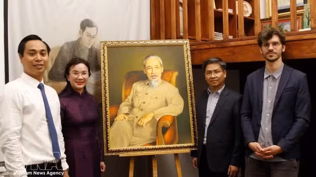La directrice du site des vestiges du président Hô Chi Minh dans la zone du Palais présidentiel, Lê Thi Phuong, le directeur du Musée de l’Histoire vivante, Thomas Le Goff (premier rang, à droite) et d’autres membres de la délégation posent avec un grand portrait du Président Hô Chi Minh. Photo : VNA.