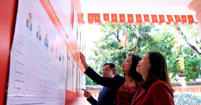 Des électeurs se rendent à un bureau de vote local pour consulter la liste des candidats à la 16e Assemblée nationale et aux conseils populaires à tous les niveaux pour le mandat 2026-2031. Photo : VNA 