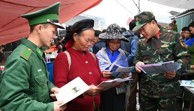 Les cadres et soldats distribuent des documents juridiques et assurent la sensibilisation auprès des habitants au marché. Photo : qdnd.vn