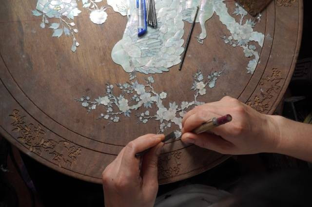 Un artisan ajuste les éléments de nacre avant la gravure – Yen Van. Photo : laodong.vn