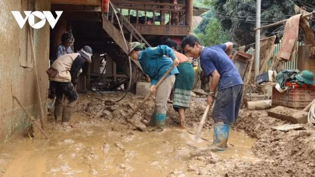 Les habitants de Suoi Lu s’entraident pour déblayer la boue et les débris. Photo : VOV.