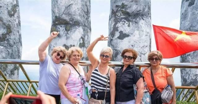 Les touristes étrangers apprécient de se prendre en photo sur le pont d’Or, orné de drapeaux vietnamiens éclatants, dans la zone touristique. Photo : baoquocte.vn