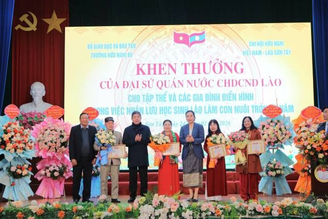 La vice-ambassadrice de la République démocratique populaire lao au Vietnam, Lattana Sihalat (cinquième en partant de la gauche), remet des certificats de mérite aux collectifs et aux familles exemplaires pour leur engagement à accueillir des étudiants laotiens comme enfants adoptifs. Photo : thoidai.com.vn
