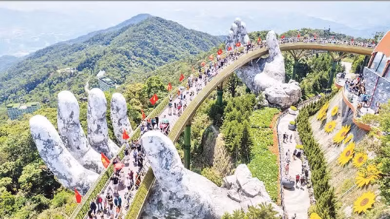 Les visiteurs admirent le paysage du pont « Cau Vang », baigné dans une mer de drapeaux rouges à étoile jaune. Photo : nhandan.vn