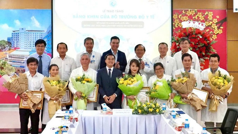 Le vice-ministre de la Santé, Tran Van Thuan, offre des fleurs et un certificat de mérite à l’équipe qui réalise une intervention fœtale sur une patiente singapourienne. Photo : nhandan.vn