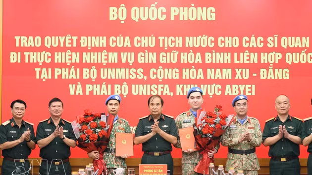 Le général de corps d’armée Phung Si Tan (au milieu) remet la décision à deux officiers de l’Armée populaire du Vietnam. Photo : VNA.