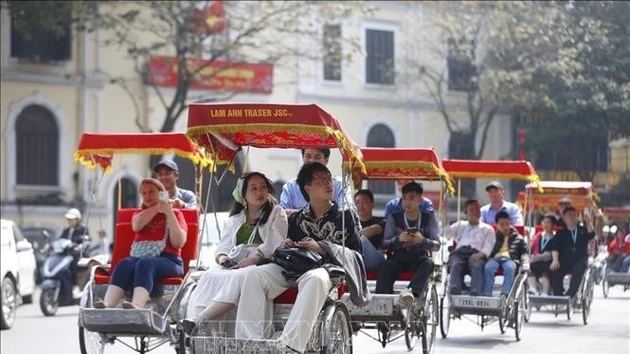 Des touristes font le tour du lac Hoan Kiem en cyclo-pousse. Photo : VNA.