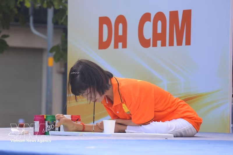 Des victimes vietnamiennes de l'agent orange réalisent des peintures avec la bouche et les pieds lors de la marche de solidarité « Pour les victimes de l'agent orange ». Photo : VNA