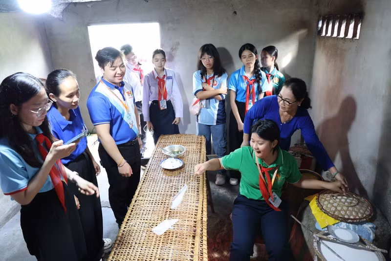 Les jeunes représentants du Vietnam, du Laos et du Cambodge ont visité plusieurs villages artisanaux de la commune de Long Dien, à Hô Chi Minh-Ville. Sur la photo, ils s'initient à la fabrication traditionnelle des galettes de riz dans le hameau d’An Ngai. Photo : tienphong.vn