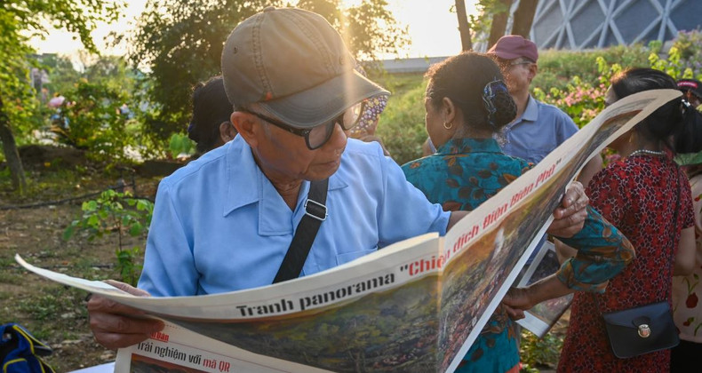 Un lecteur lit attentivement le supplément spécial du journal Nhan Dan. :Photo: NDEL