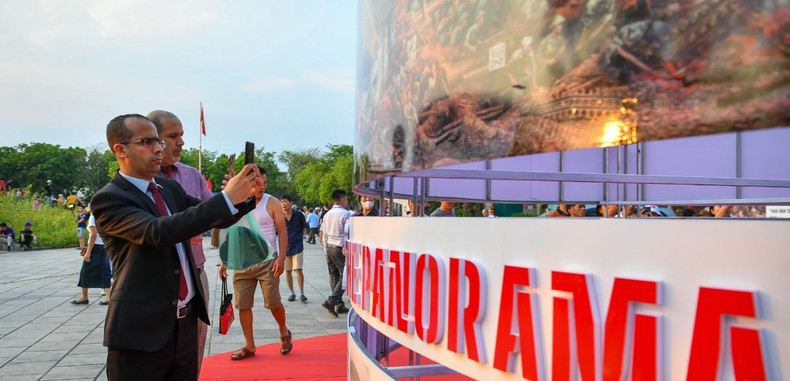 Les visiteurs étrangers expérimentent une interaction sur les peintures panoramiques de l'exposition. Photo: NDEL