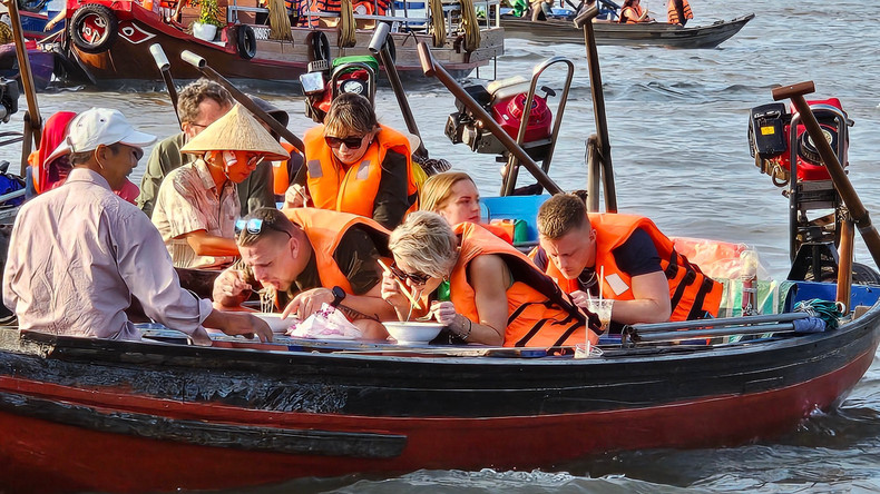 De nombreux touristes étrangers aiment prendre leur petit-déjeuner, boire du café ou déguster des fruits au milieu du marché flottant de Cai Rang. Photo : Toquoc.vn