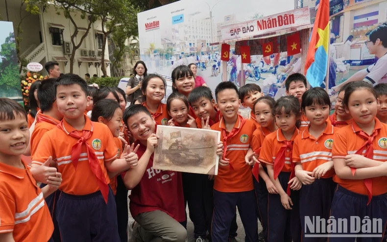 Nguyên Lac Huy, fondateur de la chaîne Schannel, pose avec l’édition spéciale aux côtés d’élèves de l’école Tràng An lors de l’exposition. Photo: nhandan.vn